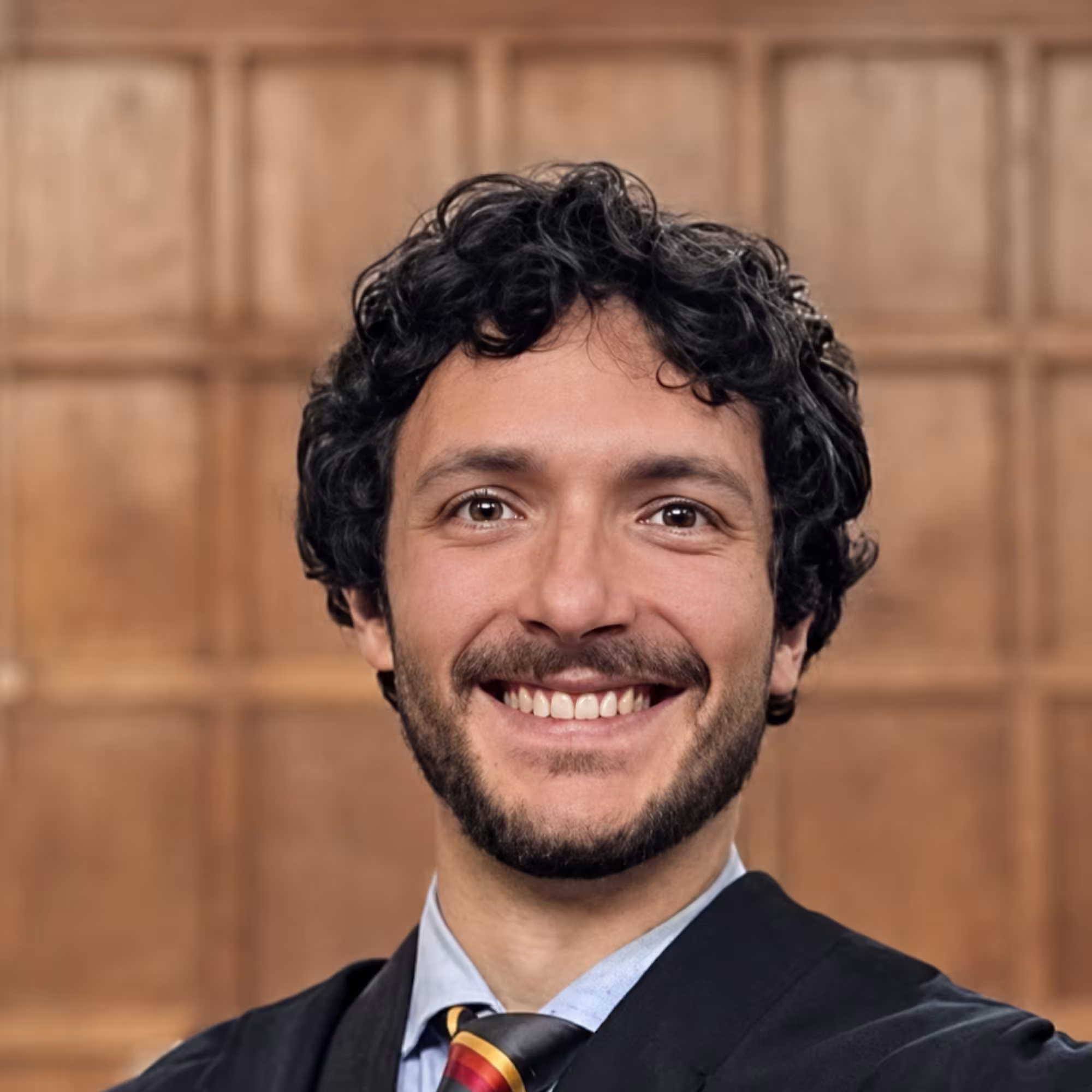 Portrait of Andrea Luppi, a white man with dark hair, moustache, wearing a smart jacket and tie. and beard