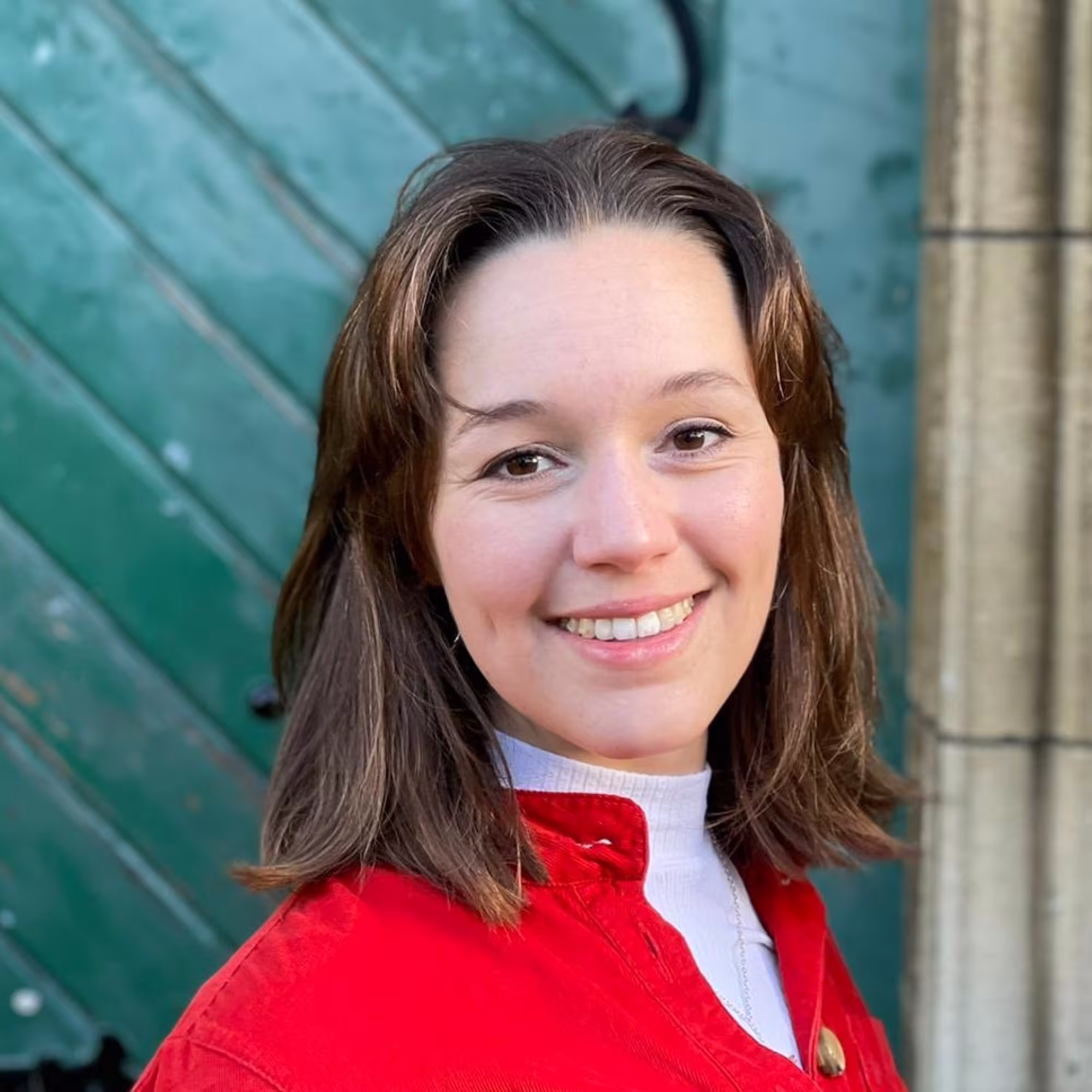 Portrait photograph of Hannah Forde, a young lady with shoulder length brown hair wearing a red jacket
