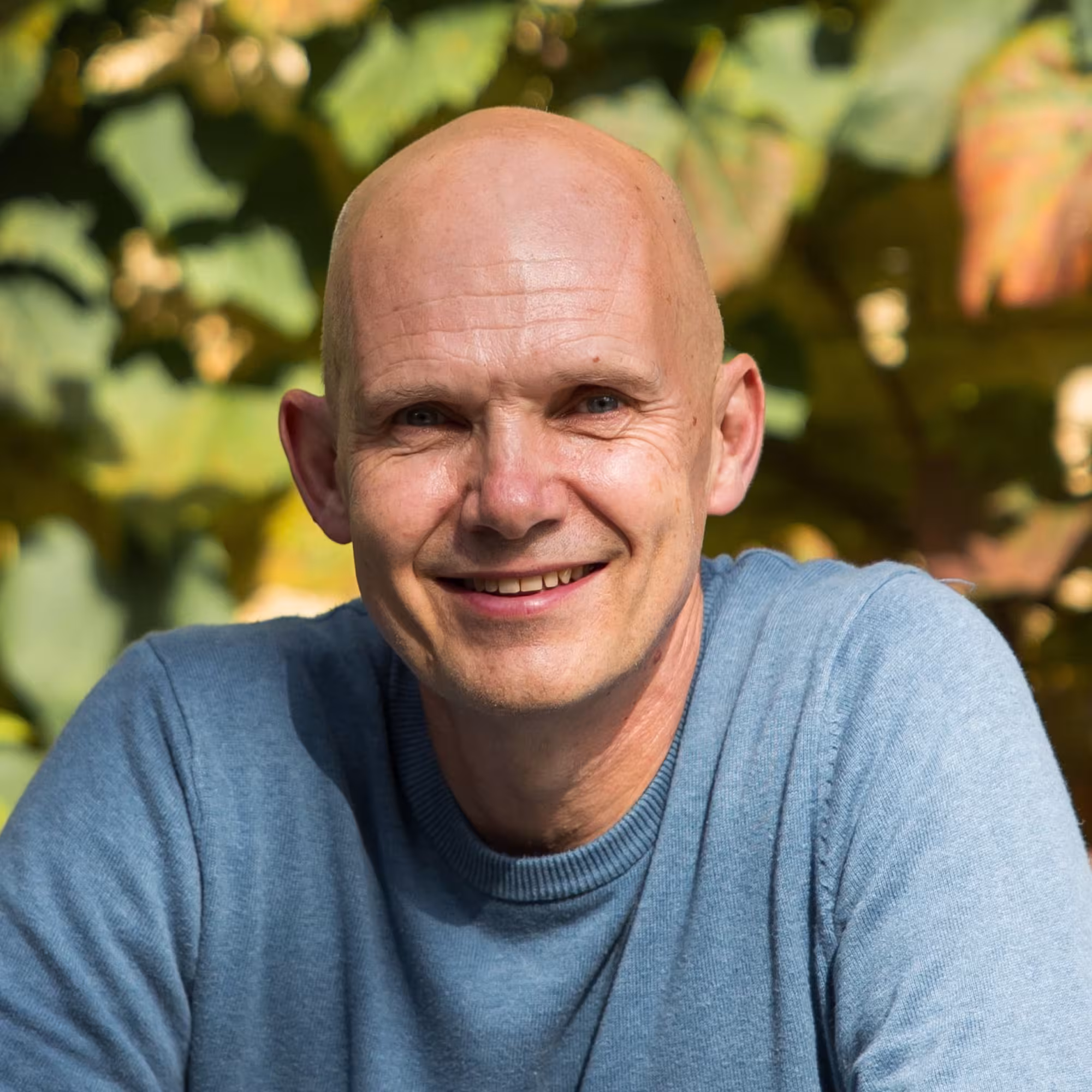 Portrait photograph of Iain McCulloch, a white man standing in front of a hedge.