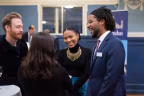 Four students stand and talk at a reception
