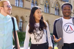 Three students walking in front of the Museum of Natural History