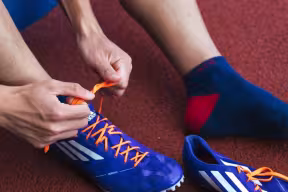 Student tying laces of running spikes on running track