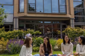 Four students sat on the grass in college grounds