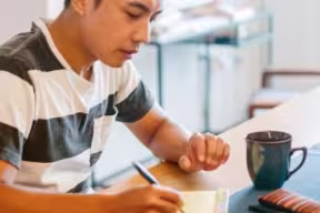 Student sat writing at a table.