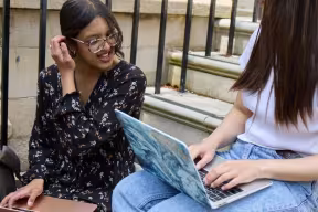 Oxford students sat on steps with laptops
