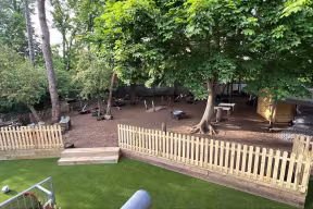The Triangle nursery garden including a tree, fencing and seating under the tree