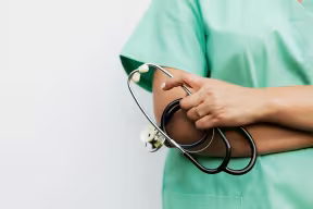Doctor in scrubs holding a stethescope