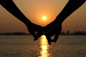 Silhouette of hands being held at sunset.
