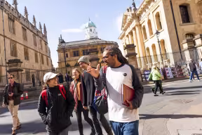 Rawz speaking to a smiling woman during a historic tour of Oxford