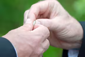 Two hands holding a wedding band