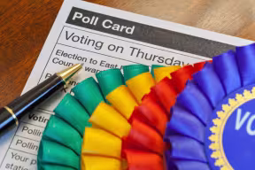 Voting in a UK Election for Members of Parliament or Representatives in Local Elections. Coloured Rosettes for the principal UK political parties.