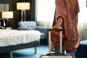 A woman in a hotel room holding a suitcase