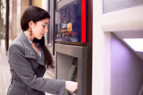 Woman using a cash machine on a city street.