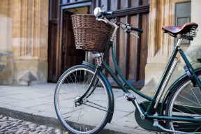 Vintage bicycle with a wicker basket parked outside a historic stone building.