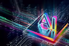 Illustration of an Artificial Intelligence processor unit, with the word 'AI' imposed above a computer chip glowing in different colours.