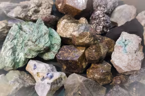 A large piece of raw malachite between other stone fragments.