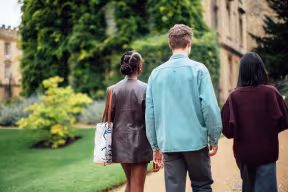 Three students walking together in the garden of a college