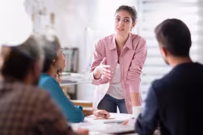 Person presenting in front of group at a table