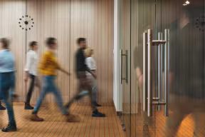 People walking through a modern office building, representing a busy workplace environment.