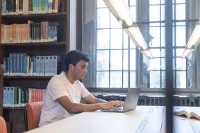 A STUDENT WORKING ON A LAPTOP IN THE RADCLIFFE SCIENCE LIBRARY