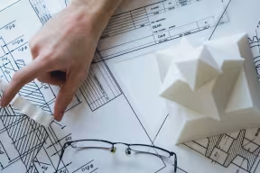 person pointing to a technical drawing on table