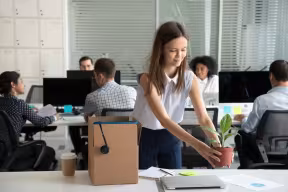 Person picking up plant from desk