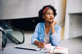 Person in blue shirts thinking and writing notes