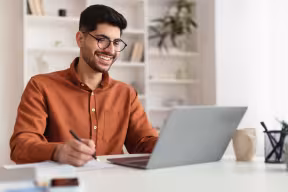 Student smiling while using laptop