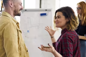 Students discussing ideas during a collaborative workshop, with a whiteboard in the background.