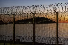 Ceuta, Spanish city in North Africa, seen from Morocco behind a thorn wire fence located on the Moroccan border against a stunning sunset over the sea