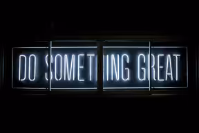 A neon lit word sign that reads 'Do Something Great'