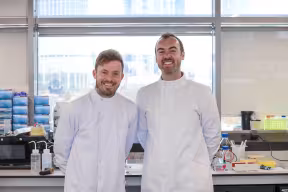 Dan Hansen and Mark Wilkinson, co-founders of Bactobio, stand together in white laboratory suits