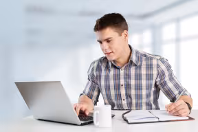 Person using laptop and writing notes