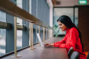 Person smiling and typing on laptop 