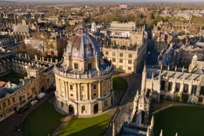 Aerial view over the Radcliffe Camera (circular building topped with a dome) and surrounding historic Oxford University colleges.