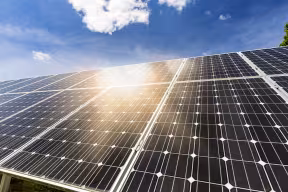 An array of solar panels with the sun shining off them