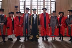 Image of all the honorands in their robes in the Divinity School with Lord Hague in the centre