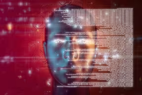 Artistic concept of artificial intelligence with a futuristic human head against a red computer chip background.