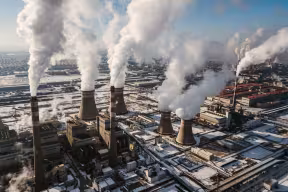 Aerial view of a coal-fired power station in winter, with clouds of carbon emissions rising from chimneys and towers.  