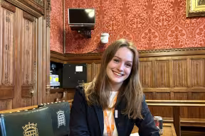 Chloe Pomfret sits at a desk in a room in the House of Commons