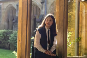 Elif Bayat sitting in a stone archway in Lincoln College