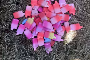 A pile of disposable e-cigarettes on the ground.