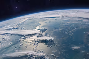Satellite image showing the surface of the blue planet Earth with ocean, clouds and continents in open space on the starry sky.