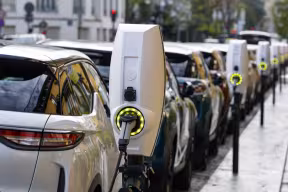 A row of electric vehicles plugged into charging points on the street.