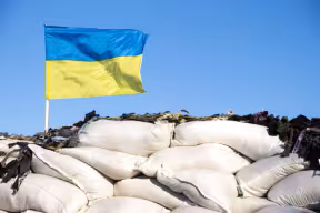 Ukrainian flag blue yellow color flutters in blue sky on barricades. Ukraine Russia War 2022. Credit: Nemer-T, Getty Images