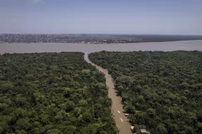 Amazon river emerges from the forest with an urban centre in the background. Credit: Anderson Coelho, Getty Images
