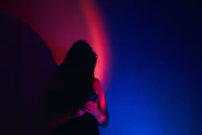 Woman reads phone in red lighting. Credit: Yuliya Taba, Getty Images