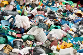 A pile of various discarded plastic items including chairs, bottles, buckets and barrels. 