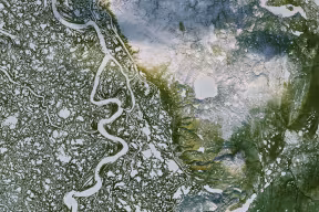 Aerial photograph of a river system in a green and rocky landscape. 