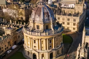 An aerial View of Radcliffe Square in Oxford. An ornate dome-shaped building in a square surrounded by historic buildings and quadrangles.